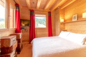 a bedroom with a bed and a window with red curtains at ORTA Chalet in Les Gets
