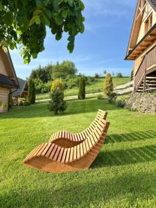 a wooden bench sitting in the grass next to a house at Pocztówka z Mizernej, drewniane domki, widok na Tatry, blisko Velo Czorsztyn, Jezioro Czorsztyńskie, rowery, spokojna okolica in Kluszkowce +185 photos