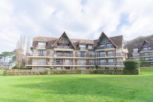a large building with a green field in front of it at Le Sommet du Large - Terrasse - Vue Mer - Parking Privé in Trouville-sur-Mer