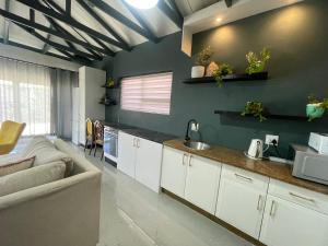 Blouberg kiters في Cape Town: مطبخ مع دواليب بيضاء واريكة في الغرفة