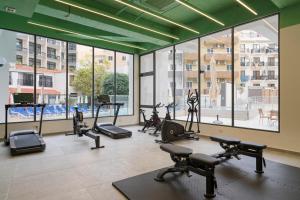 a gym with several treadmills and ellipticals and windows at Cora Sun Apart-Hotel in St Paul's Bay