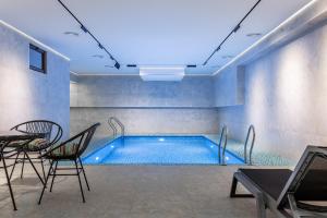 a swimming pool with chairs and a table in a room at Silk Road Tashkent in Tashkent