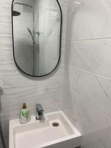 a white bathroom with a sink and a mirror at Angenellyq apartment in Kyustendil