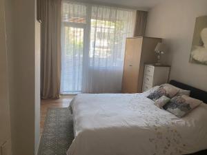 a bedroom with a white bed and a window at Angenellyq apartment in Kyustendil