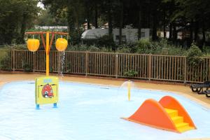 a swimming pool with two play equipment in it at Camping Le Val de Trie in Béhen