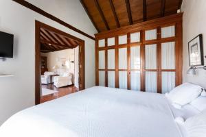 a bedroom with a white bed and a living room at GuestReady - Hotel Rural Las Calas in Vega de San Mateo