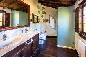 a bathroom with two sinks and a toilet and a mirror at GuestReady - Hotel Rural Las Calas in Vega de San Mateo