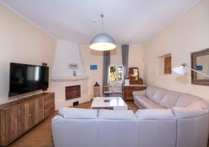 a living room with a white couch and a tv at Villa Arancia Private Pool, 2 Jacuzzis & BBQ Area in Pigi