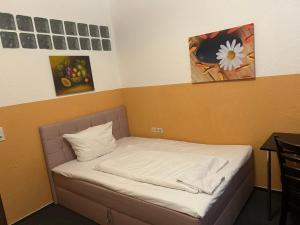 a small bed in a room with paintings on the wall at Hotel RI in Esslingen