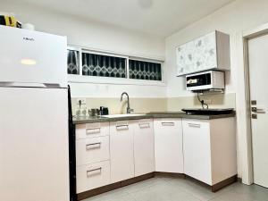 a white kitchen with a sink and a refrigerator at The Urban Suite in Petaẖ Tiqwa