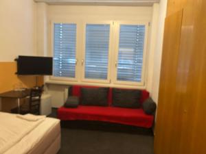 una camera con un divano rosso di fronte a una finestra di Hotel RI a Esslingen