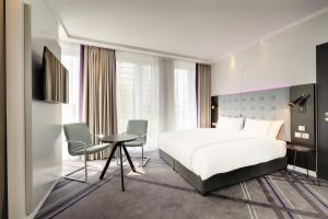 a bedroom with a white bed and a desk and chairs at Premier Inn Duisburg City Altstadt in Duisburg
