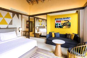 a bedroom with a bed and a couch and a table at Hard Rock Hotel Maldives - FREE shared speedboat for stays from 01st Mar to 31st Oct 2026 in South Male Atoll