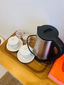 a tea kettle on a wooden table with plates and cups at Pinggan harmoni in Baturaja