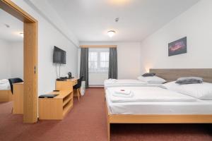 a hotel room with two beds and a desk at Hotel Arena Liberec in Liberec