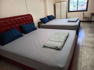 乌汶Doctor Thanut Hostel的客房配有两张带蓝色枕头的床。