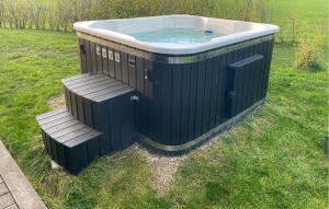 Una bañera sentada en el césped con un banco. en Awesome Home In Føllenslev With Wifi, en Havnsø