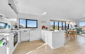 cocina con armarios blancos y comedor en Awesome Home In Føllenslev With Wifi, en Havnsø