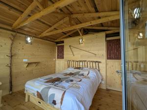 a bedroom with a bed in a wooden cabin at "La cabane", la roseraie de Zoubiroux in Saint-Geneys-près-Saint-Paulien +5 photos