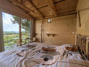 a bedroom with a bed in a room with a window at "La cabane", la roseraie de Zoubiroux in Saint-Geneys-près-Saint-Paulien