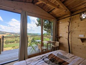 a bedroom with a bed and a large window at "La cabane", la roseraie de Zoubiroux in Saint-Geneys-près-Saint-Paulien