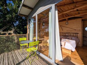 a room with a balcony with a bed and a table and chairs at "La cabane", la roseraie de Zoubiroux in Saint-Geneys-près-Saint-Paulien