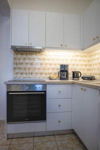 a kitchen with white cabinets and a black oven at Fotis House 3 in Afantou +7 photos