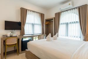 a hotel room with a bed and a desk with a television at Finn Hotel in Ban Fang Daeng