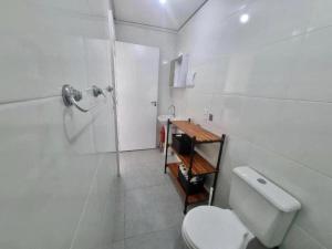 a white bathroom with a toilet and a shower at Espaço inteiro e tranquilo in São José
