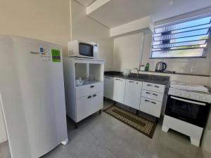 a kitchen with a white refrigerator and a microwave at Espaço inteiro e tranquilo in São José