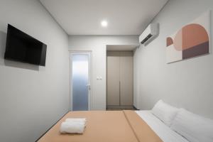 a small white room with a bed and a flat screen tv at Cove Anasera in Jombang