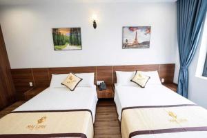 two beds in a room with blue curtains at Mai Linh Hotel in Ha Long