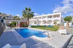 a villa with a swimming pool in front of a building at Apto 2 Almoraide Suites in Nerja