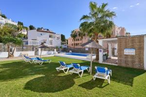a yard with chairs and umbrellas and a pool at Apto 2 Almoraide Suites in Nerja