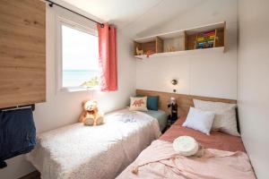 a bedroom with two beds and a teddy bear sitting on the bed at Camping le Héron in Dolus-d'Oléron +45 photos