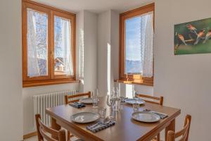 a dining room with a table and chairs and two windows at Surgiva del Sòm in Folgaria