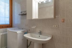 a bathroom with a sink and a toilet and a mirror at Surgiva del Sòm in Folgaria
