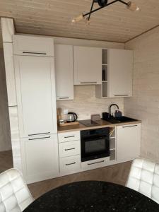 a kitchen with white cabinets and a black table at Bobrowa Przystań in Bolesławiec
