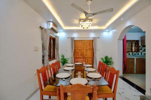 a dining room with a table with chairs and a ceiling fan at Hotel Eyokar Goa in Candolim