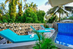 a patio with blue chairs and a swimming pool at Hotel Eyokar Goa in Candolim