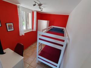a bedroom with a bunk bed in a room with red walls at Alba e Colori di Puglia in Conversano