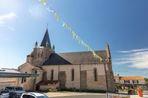 an old church with a steeple and cars parked in front at Camping Clos Cottet in Angles