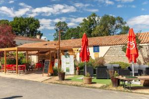 a restaurant with red umbrellas and tables and chairs at Camping Clos Cottet in Angles