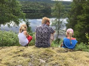 un uomo e due ragazze seduti su una collina vicino a un lago di Øyungen 2 a Namsos