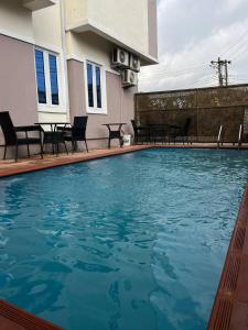 Una gran piscina con sillas y una mesa. en Maxwells Inn Yaba, en Lagos 5 fotos más