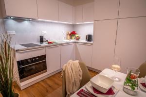 a small kitchen with white cabinets and a table with a table at Sweet Embrace in Brno
