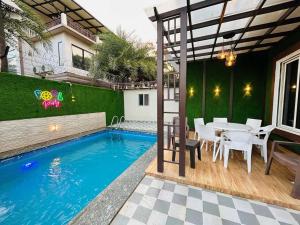 Nakshatra Villa by Palette Homes | 4BHK | Gazebo | BBQ | Pool | Rain Dance | Lonavala في لونافالا: منزل به مسبح وطاولة وكراسي