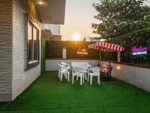 Nakshatra Villa by Palette Homes | 4BHK | Gazebo | BBQ | Pool | Rain Dance | Lonavala في لونافالا: فناء مع طاولات وكراسي بيضاء على العشب