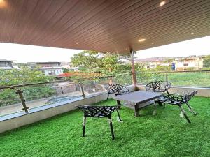 Nakshatra Villa by Palette Homes | 4BHK | Gazebo | BBQ | Pool | Rain Dance | Lonavala في لونافالا: فناء مع طاولة وكراسي على شرفة +13 صورة