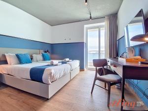 a bedroom with a bed and a desk and a computer at South 32 Hotel by Zzzing in Birżebbuġa